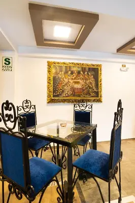 a table and chairs with a painting on the wall at Hotel Hacienda Cusco Centro Historico in Cusco