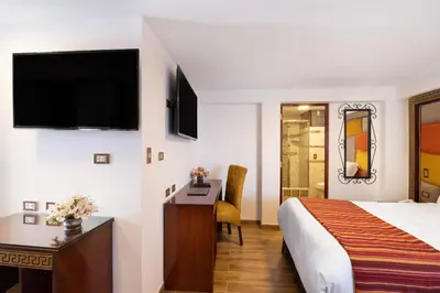 a hotel room with a bed and a desk and a television at Hotel Hacienda Cusco Centro Historico in Cusco