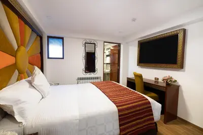 a hotel room with a bed and a desk and a television at Hotel Hacienda Cusco Centro Historico in Cusco