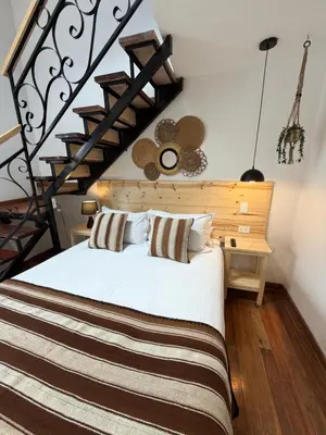 a bedroom with a white bed and a staircase at CASA CRISTOBAL Siete Cuartones in Cusco