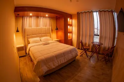a bedroom with a bed and a table and a window at Besso Beach Hotel in Barranca