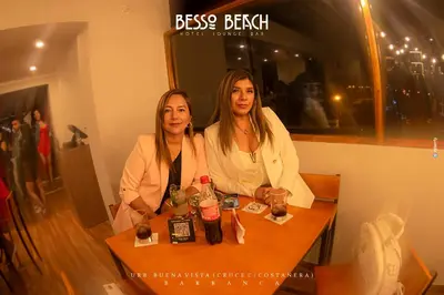 two women sitting at a table with drinks at Besso Beach Hotel in Barranca