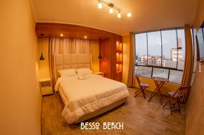 a bedroom with a bed and a table and a window at Besso Beach Hotel in Barranca