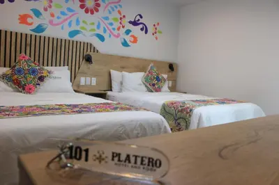 a hotel room with two beds and a table at Platero Hotel in Ayacucho
