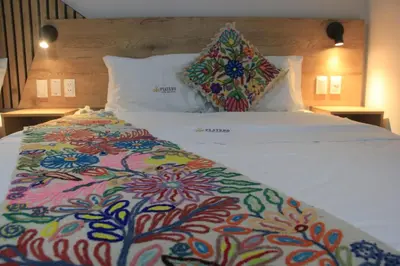 a large white bed with a colorful blanket on it at Platero Hotel in Ayacucho