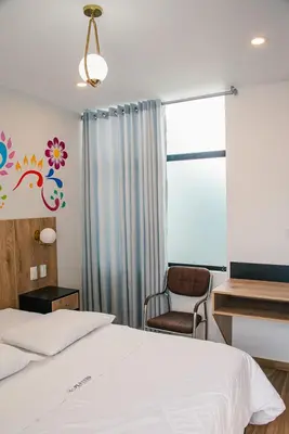a bedroom with a bed and a chair and a window at Platero Hotel in Ayacucho