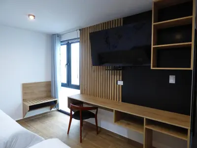 a bedroom with a desk and a tv on a wall at Platero Hotel in Ayacucho