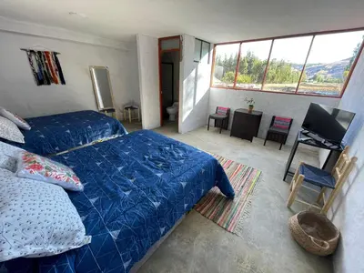 a bedroom with a blue bed and a television in it at CasaHotel Laguna Jauja Airport in Jauja