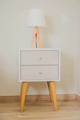 a white bedside table with a lamp on it at Bungalow Jatun Mama in Ventanilla