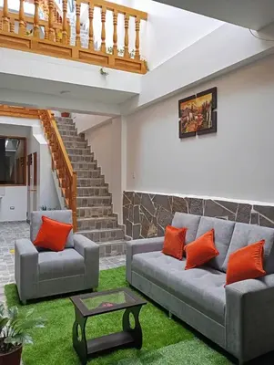 a living room with two gray couches and orange pillows at Qente Wings in Ollantaytambo
