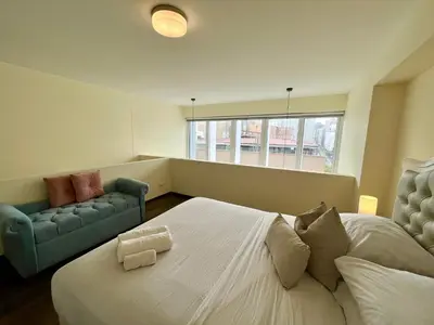a bedroom with a large white bed and a couch at Elegante Duplex Cerca Parque Kennedy Miraflores in Lima