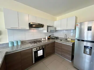 a kitchen with white cabinets and a stainless steel refrigerator at Elegante Duplex Cerca Parque Kennedy Miraflores in Lima
