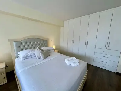 a white bedroom with a large bed with white cabinets at Elegante Duplex Cerca Parque Kennedy Miraflores in Lima