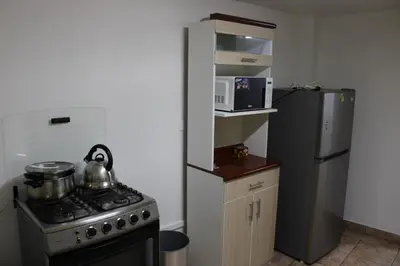 a small kitchen with a stove and a refrigerator at Hospedaje San Isidro in Lima