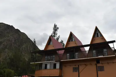 a building with pointed roofs with mountains in the background at New Experiences Valle sagrado in Urubamba