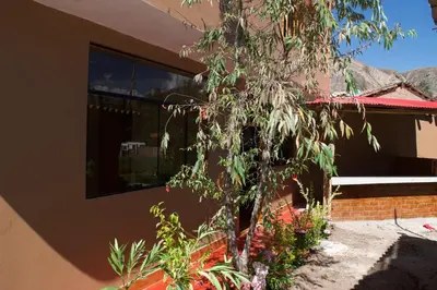 a house with a tree in front of a building at New Experiences Valle sagrado in Urubamba