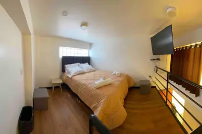 a bedroom with a bed and a flat screen tv at Loft en centro histórico Cusco Inlove in Cusco