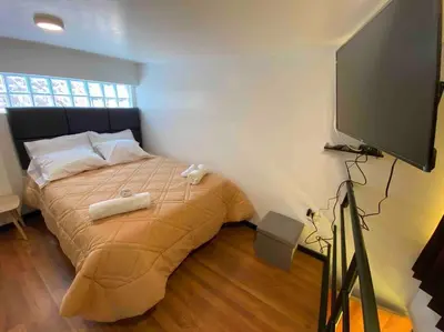 a bedroom with a bed and a flat screen tv at Loft en centro histórico Cusco Inlove in Cusco