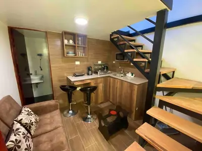 a small room with a kitchen and a spiral staircase at Loft en centro histórico Cusco Inlove in Cusco