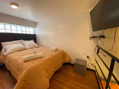 a bedroom with a bed and a flat screen tv at Loft en centro histórico Cusco Inlove in Cusco