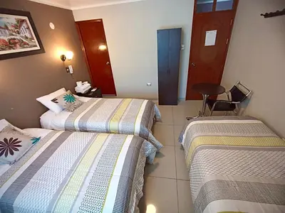 a hotel room with two beds and a table at Kametza Hotel Ayacucho in Ayacucho