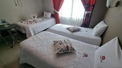a room with two beds and a table and a window at Kametza Hotel Ayacucho in Ayacucho