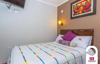 a bedroom with a bed with colorful sheets and pillows at Kametza Hotel Ayacucho in Ayacucho
