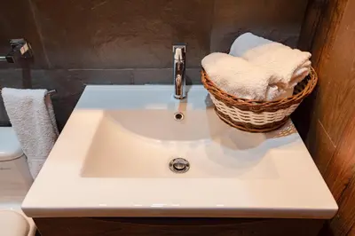 a bathroom sink with a basket of towels on it at Town Center Apartments in Urubamba