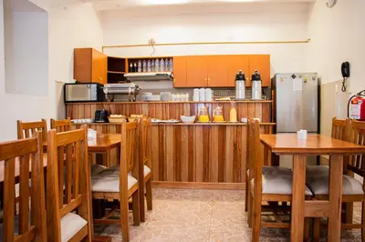a kitchen with wooden chairs and tables and a refrigerator at Estancia San Pedro Hotel in Cusco