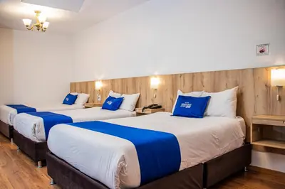 two beds in a hotel room with blue pillows at Estancia San Pedro Hotel in Cusco