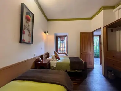 a bedroom with two beds and a mirror and a door at Terra Sagrada Cusco in Cusco