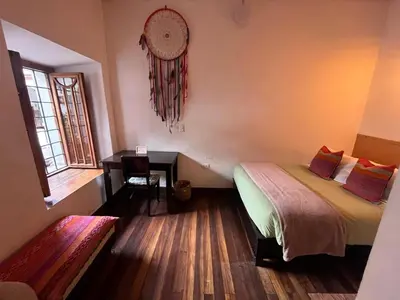 a bedroom with a bed and a table and a window at Terra Sagrada Cusco in Cusco
