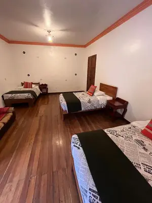 a room with three beds and a wooden floor at Terra Sagrada Cusco in Cusco
