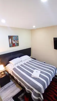 a bedroom with a large bed with a striped blanket at Apartamento JATUN MAMA in Chancay