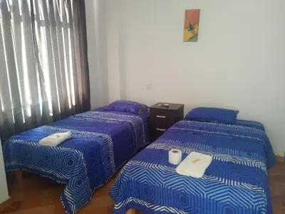 two beds in a room with blue and white sheets at La Petite Maison in Nazca
