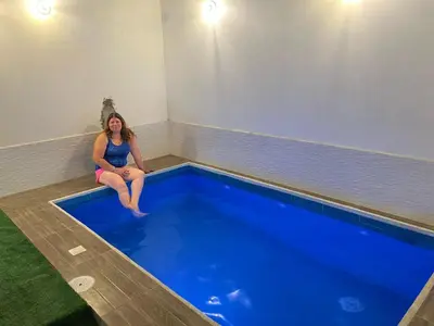a woman sitting on the edge of a swimming pool at La Petite Maison in Nazca
