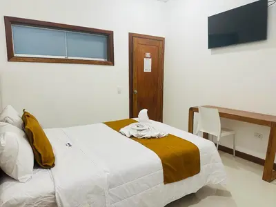 a bedroom with a bed and a desk and a television at Hotel Overland in Paracas