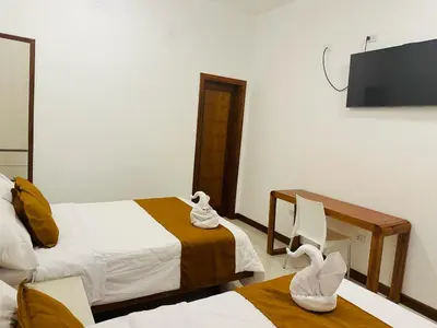 a hotel room with two beds and a flat screen tv at Hotel Overland in Paracas