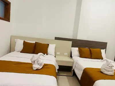 two beds with towels on them in a room at Hotel Overland in Paracas