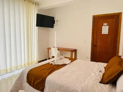 a bedroom with a large bed with white sheets at Hotel Overland in Paracas