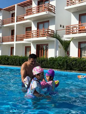 a man and two children in the water in a swimming pool at Hotel La Colina in Ica