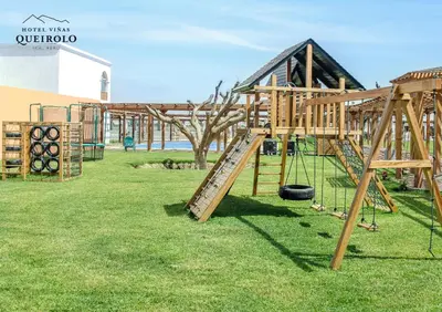 a playground with wooden play equipment on the grass at Hotel Viñas Queirolo in Ica