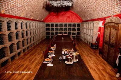 a dining room with a long table with wine bottles at Hotel Viñas Queirolo in Ica