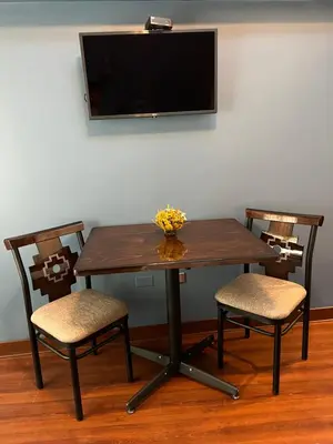 a wooden table with two chairs and a television on a wall at Hotel Andina in Cusco