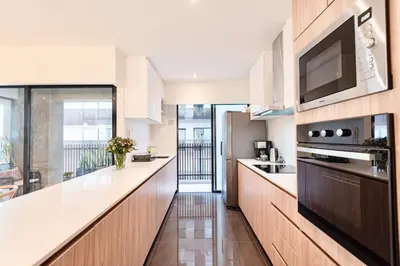 a kitchen with white counters and a television on the wall at ✶ Maras Residence ✶ LUXURY Rooftop Pool & Grill in Lima