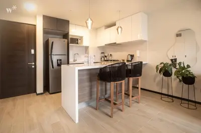a kitchen with white cabinets and black appliances at Pionero by Wynwood House in Lima