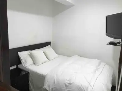 a white bed in a room with a tv at Minidepartamento céntrico entre Lince y San Isidro in Lima