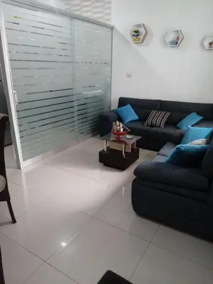 a living room with a black couch and blue pillows at Departamento con servicios incluidos, equipado in Lima