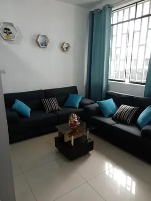 a living room with a black couch and blue pillows at Departamento con servicios incluidos, equipado in Lima