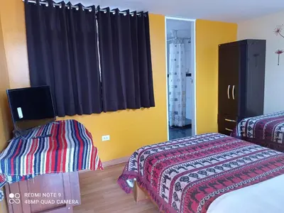 a bedroom with two beds and a window with curtains at Nature Home Cusco in Cusco